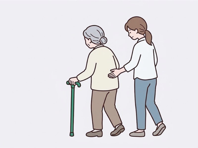 杖で歩く高齢の方の、やや斜め後ろに立って、見守る家族のイメージ